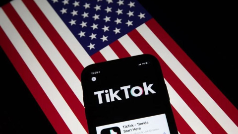 Un móvil con la aplicación China TikTok, sobre una bandera de EEUU.