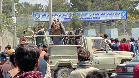 Los talibanes montan guardia frente al aeropuerto internacional Jamid Karzai mientras la gente camina hacia el aeropuerto para huir del país.