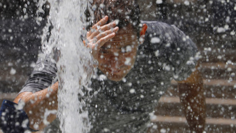 Un hombre se refresca en una fuente de Córdoba.