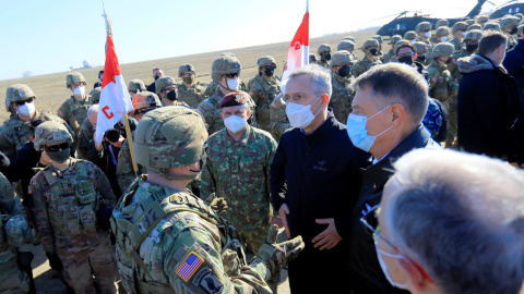 El secretario general de la OTAN, Jens Stoltenberg (C), y el presidente de Rumania, Klaus Iohannis (D), hablan con un oficial al mando de EE. UU. en la base aérea militar de Mihail Kogalniceanu, Rumania, el 11 de febrero de 2022.