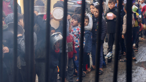 22/12/23 . Niños palestinos cargan ollas mientras hacen cola para recibir comida cocinada en una cocina benéfica en Rafah, en el sur de la Franja de Gaza.