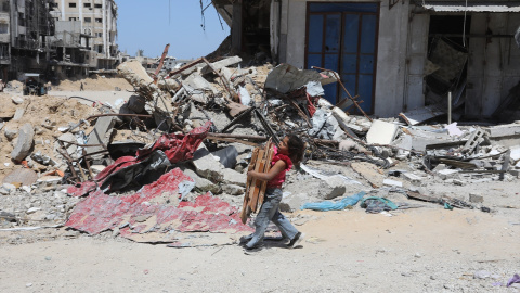 19/04/2924 Un niño palestino sostiene madera junto a las ruinas de edificios destruidos por los bombardeos israelíes, a 13 de abril de 2024.