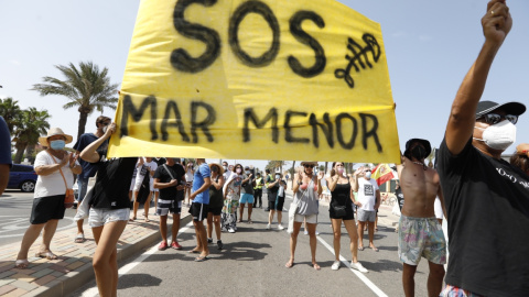 Varias personas participan en una protesta en defensa del Mar Menor al paso de la Vuelta Ciclista a España, a 21 de agosto de 2021, en La Manga.