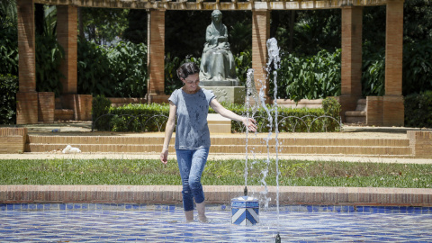 Una mujer se refresca en una fuente en plena ola de calor en Sevilla durante la primera ola de calor de 2023, a finales del mes de junio.