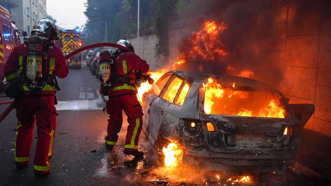 Los bomberos extinguen el fuego en un coche en llamas tras los disturbios en el distrito de Nanterre