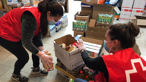 Dues voluntàries de Creu Roja preparen lots d'aliments.