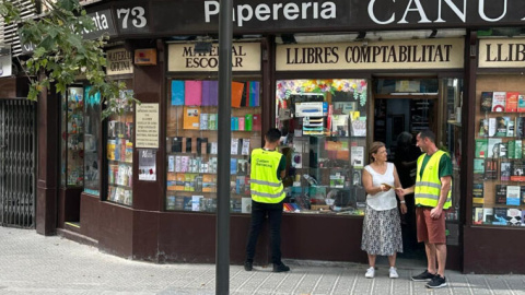 Dos informadores hablando con la responsable de un comercio.