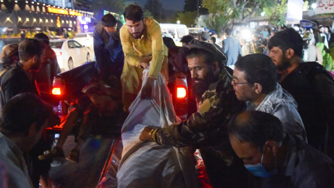 Voluntarios y personal médico descargan de una camioneta frente a un hospital el cuerpo de uno de los fallecidos en los atentados en Kabul. AFP/Wakil KOHSAR