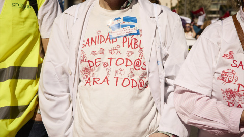 Varias personas, algunas con batas blancas, marchan en la manifestación convocada por entidades sociales, profesionales de la sanidad y organizaciones sindicales por la defensa del sistema sanitario público madrileño, a 26 de marzo de 2023, en Madrid (