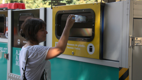 Una dona llençant una ampolla de plàstic a una plataforma de recollida selectiva mòbil al barri de Bon Pastor de Barcelona.