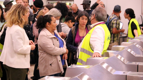 Treballadors regulen l'accés dels viatgers a les andanes de l'Estació de Sants aquest diumenge.