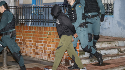 El presunto asesino de tres hermanos en Morata de Tajuña, Dilawar Hussein F.C., sale custodiado por guardias civiles tras el registro de su vivienda en Arganda del Rey.