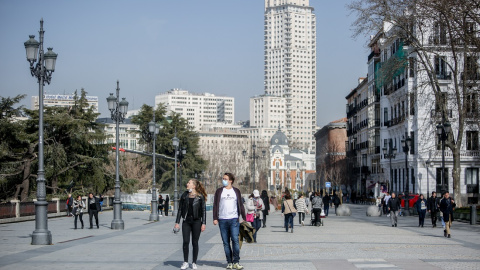 Una mujer camina sin mascarilla y un hombre con mascarilla, a 10 de febrero de 2022, en Madrid