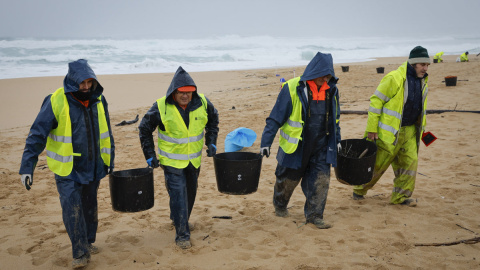 Operarios retiran los pellets o bolitas para fabricar plástico que han aparecido en las playas gallegas y de Asturias.