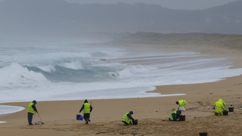 Operarios de empresas contratadas por la Xunta retiran los pellets o bolitas para fabricar plástico que aparecen en las playas gallegas y de Asturias, tras la caída de un contenedor de un barco el pasado diciembre, esta mañana en la playa de O Vilar, e