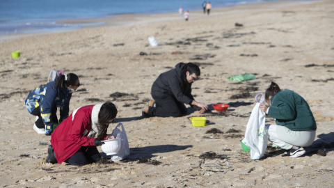 Voluntarios recogen microeplásticos o pellets, que han aparecido en toda la costa atlántica de Galicia, este domingo en la Playa de A Lanzada en O Grove.