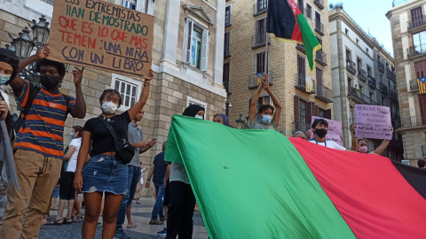 La comunitat afgana sosté una bandera gegant de l'Afganistan durant la mobilització a la plaça Sant Jaume de rebuig contra l'emirat proclamat pels talibans.