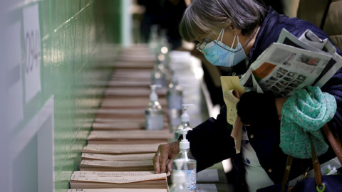 04/05/2021.- Una mujer escoge una papeleta para ejercer su derecho al voto en el colegio La Inmacualada-Marillac en Madrid durante la jornada electoral.