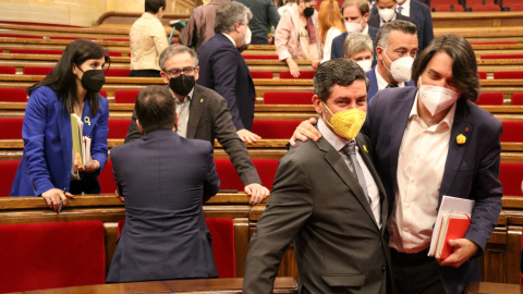 Pla conjunt dels negociadors d'ERC i Joan Candell i Francesc de Dalmases (JxCat) passant pel costat a l'hemicicle del Parlament el 13 d'abril del 2021.