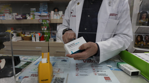 Un farmacéutico recorta el código de barras de una caja de Paracetamol en su farmacia, en Madrid a 20 de abril de 2020