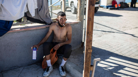 Un joven descansa fumándose un cigarrillo tras haber cruzado a nado la frontera de Ceuta con Marruecos.