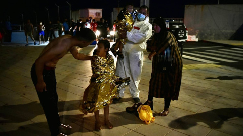 Un hombre migrante coge en brazos a un menor acompañado de una mujer y una niña pequeña, a 17 de mayo de 2021, en Ceuta (España).