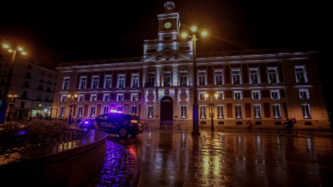 Un coche de la Policía Nacional circula en la Puerta del Sol durante la primera noche de toque de queda en Madrid