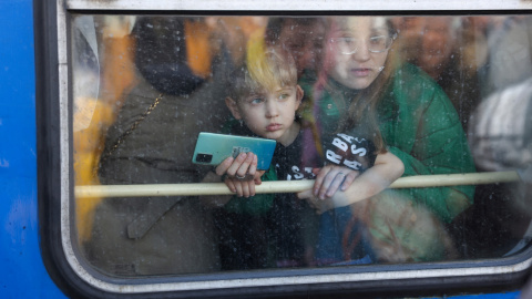 Una mujer y su hijo miran desde un tren de evacuación de Kiev a hacia la ciudad de Lviv (Leópolis) en la estación central de trenes de Kiev, en el segundo día la invasión rusa.