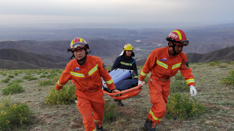 Equipos de emergencia llevan una camilla en las operaciones de búsqueda de 21 atletas que fallecieron en una carrera de montaña.