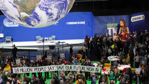 Un grupo de personas realiza una protesta en la COP26 con una pancarta que reza: "1,8 millones de personas dicen: salvad nuestro futuro ahora".