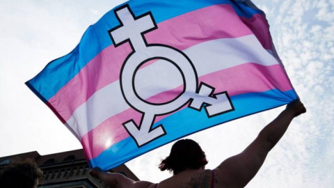 Una persona ondea una bandera trans.