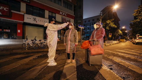 Un voluntario toma la temperatura a una mujer embaraza en la ciudad china de Wuhan. - EFE