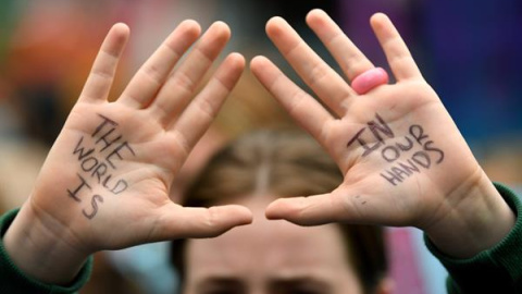 "El mundo está en nuestras manos", es la leyenda escrita a bolígrafo que muestra en las palmas de sus manos un estudiante que participa en el acto de protesta "School Strike 4 Life" en Sidney, Australia, este viernes.