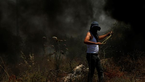 Un manifestante lanza piedras con su honda a miembros de las tropas israelíes después de una protesta contra unos asentamientos israelíes, este viernes en Nablus, Palestina.