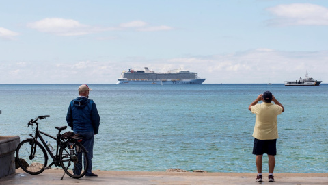 Unos hombres observan el crucero turístico "Odissey of the Seas" fondeando este lunes en la bahía de Palma de Mallorca.