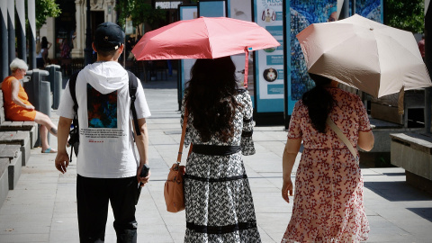 Varios turistas se cubren del sol con sombrillas mientras pasean este martes por Sevilla.