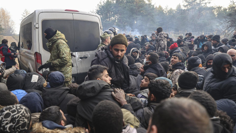 Refugiados y migrantes se agolpan para recibir ayuda humanitaria distribuída por soldados bielorrusos en un campo en la frontera con Polonia en la región de Grodno.