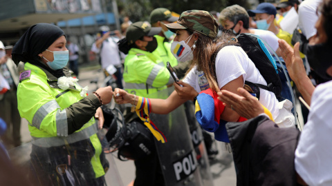 Una mujer golpea los puños con un oficial de policía mientras la gente marcha en oposición a los bloqueos de carreteras y la violencia después de un mes de protestas nacionales, en Bogotá, Colombia.