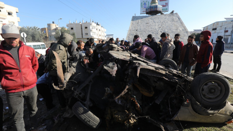 Palestinos alrededor de un vehículo dañado por los ataques israelíes.