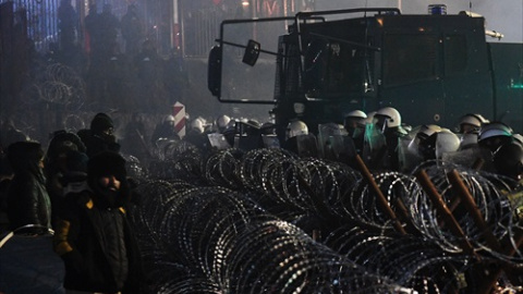 Campamento de refugiados en el paso fronterizo de Bruzgi-Kuznica Bialostocka mientras los militares polacos hacen guardia detrás de una valla cerca de la frontera bielorrusa-polaca, a 15 de noviembre de 2021, en Bruzgi, (Bielorrusia).