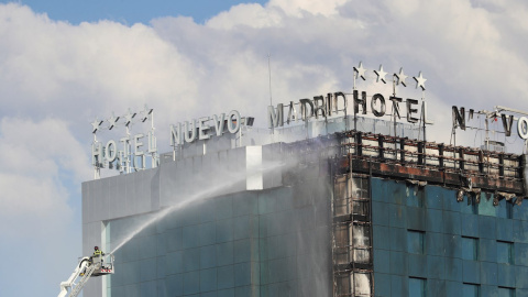 Bomberos extinguen las llamas tras un aparatoso incendio en la fachada exterior del Hotel Nuevo Madrid, situado junto a la zona norte de la M-30 en Madrid, este jueves.