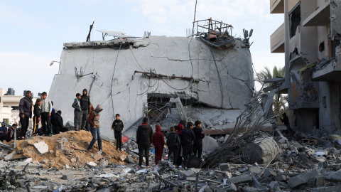 Un grupo de palestinos cerca de una casa derruida por un ataque israelí, en Rafah, en el sur de la Franja de Gaza. REUTERS/Ibraheem Abu Mustafa