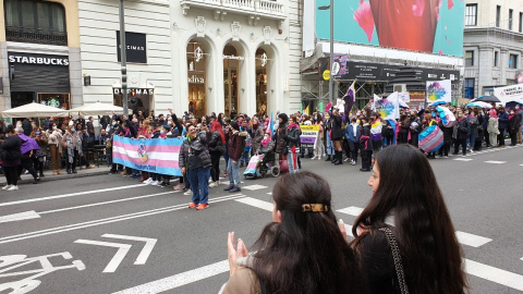 Dos transeúntes aplauden a los manifestantes a favor de la ley trans en la Gran Vía de Madrid.