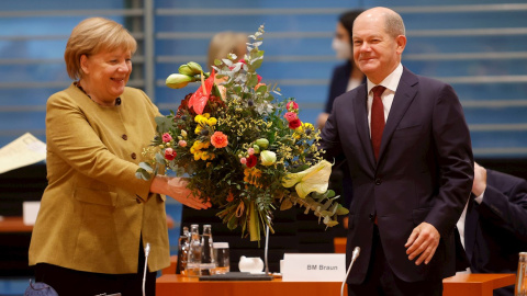 La canciller interina Angela Merkel recibe un ramo de flores del ministro de Finanzas y vicecanciller interino Olaf Scholz.