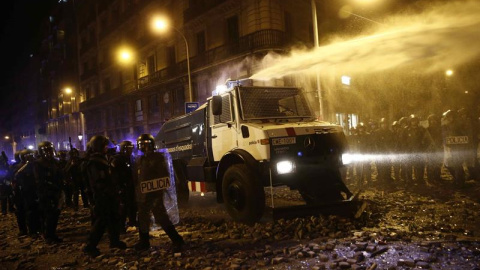 Un grupo de policías antidisturbios junto a la tanqueta de agua a presión durante los altercados que se están produciendo en Barcelona este viernes. /EFE