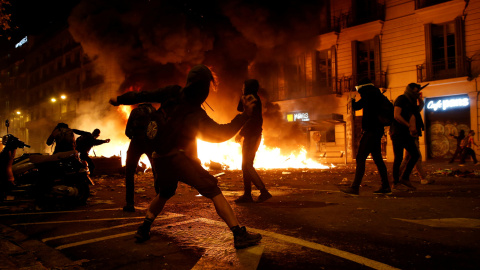 Un grupo de radicales en una barricada incendiada lanzando objetos a los Mossos en Barcelona. /REUTERS