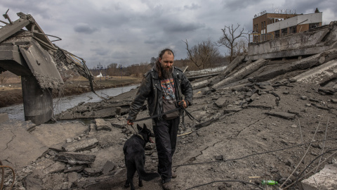 Un hombre con su perro cruza el puente destruido mientras huyen de la ciudad de primera línea de Irpin, región de Kiev (Kiev), Ucrania, 07 de marzo de 2022.