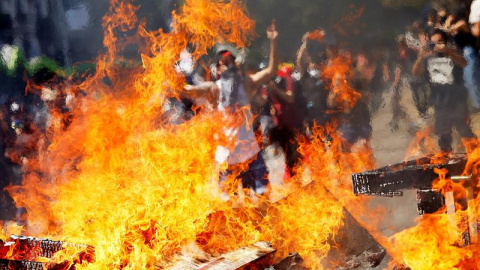 Un manifestante salta este lunes frente a una barricada en el centro de la capital sector Plaza Italia durante una nueva jornada de masivas protestas en Santiago (Chile). EFE/Esteban Garay