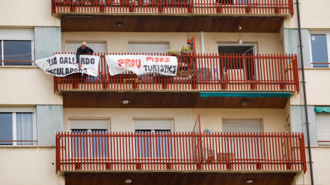 Un hombre coloca una pancarta en el balcón de su casa en protesta por los pisos turísticos del edificio en el que vive, en el barrio de Sants en Barcelona. La pancarta dice "No más pisos turísticos". REUTERS/Albert Gea