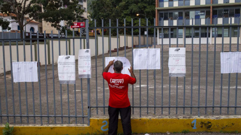 Un hombre busca su nombre en las hojas del padrón electoral a la entrada de un colegio electoral durante las elecciones regionales y municipales en Caracas, el 21 de noviembre de 2021.